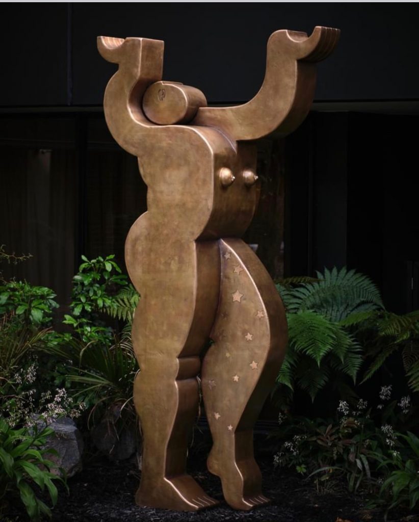 As guests arrive at Cordis Auckland, they are greeted
by Holding up the Sky, a 3.5-metre bronze representation
of Ika-roa, Māori Mother Goddess. Her arms reach to the
sky, protecting all those who pass beneath her. In Māori
mythology, Ika-roa is the Mother Goddess of all the stars,
the ornaments of the sky. Ika-Roa is also an alternative
name for the Milky Way. The work speaks of kaitiakitanga,
our guardianship and interconnectedness with the stars
and with the earth. As the goddess, she stands firm on the
ground while she holds up the stars.